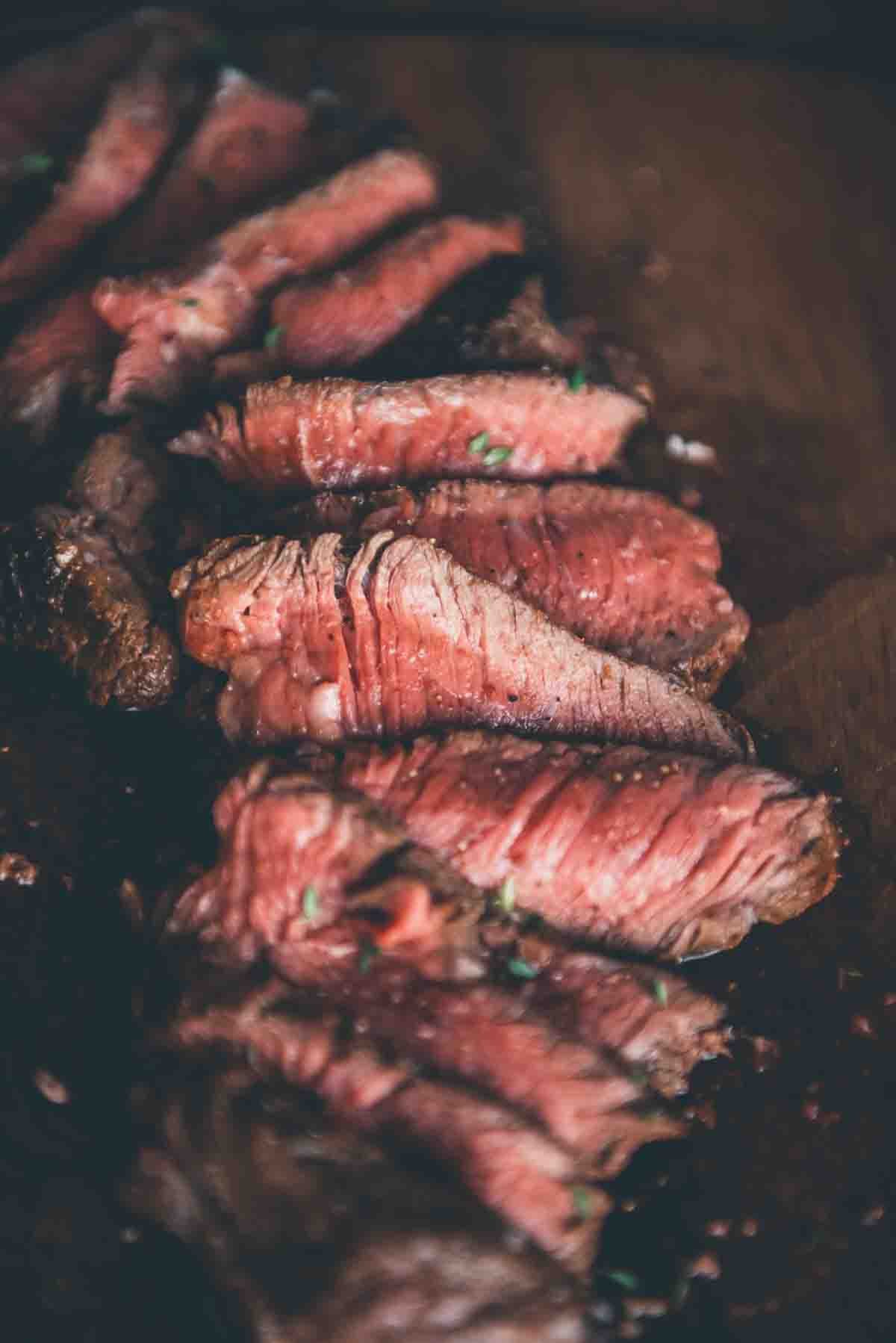 Close up of cooked steak sliced thin to show the grain and a medium rare center. 