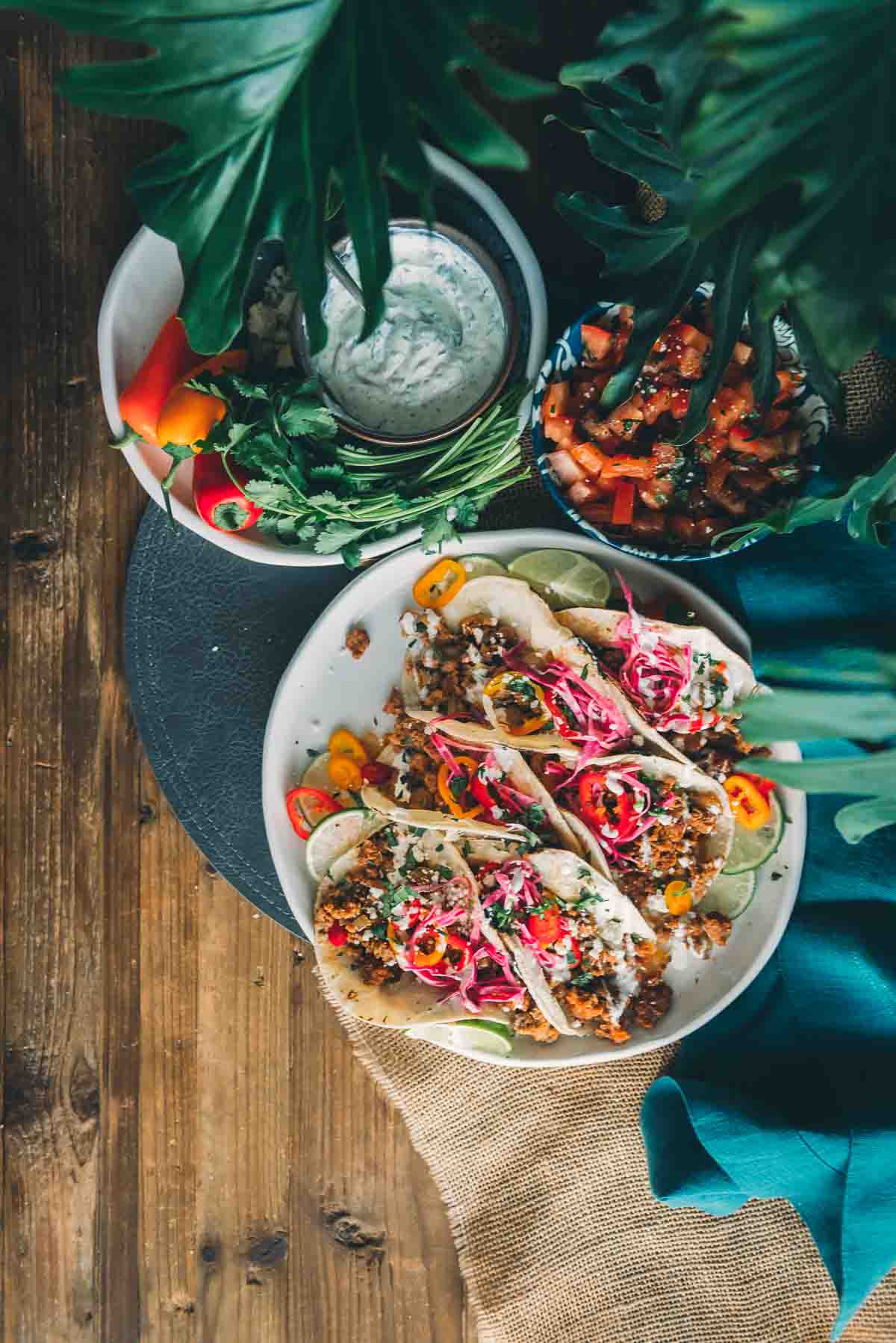 Colorful overhead shot of platter with street tacos and toppings near by. 