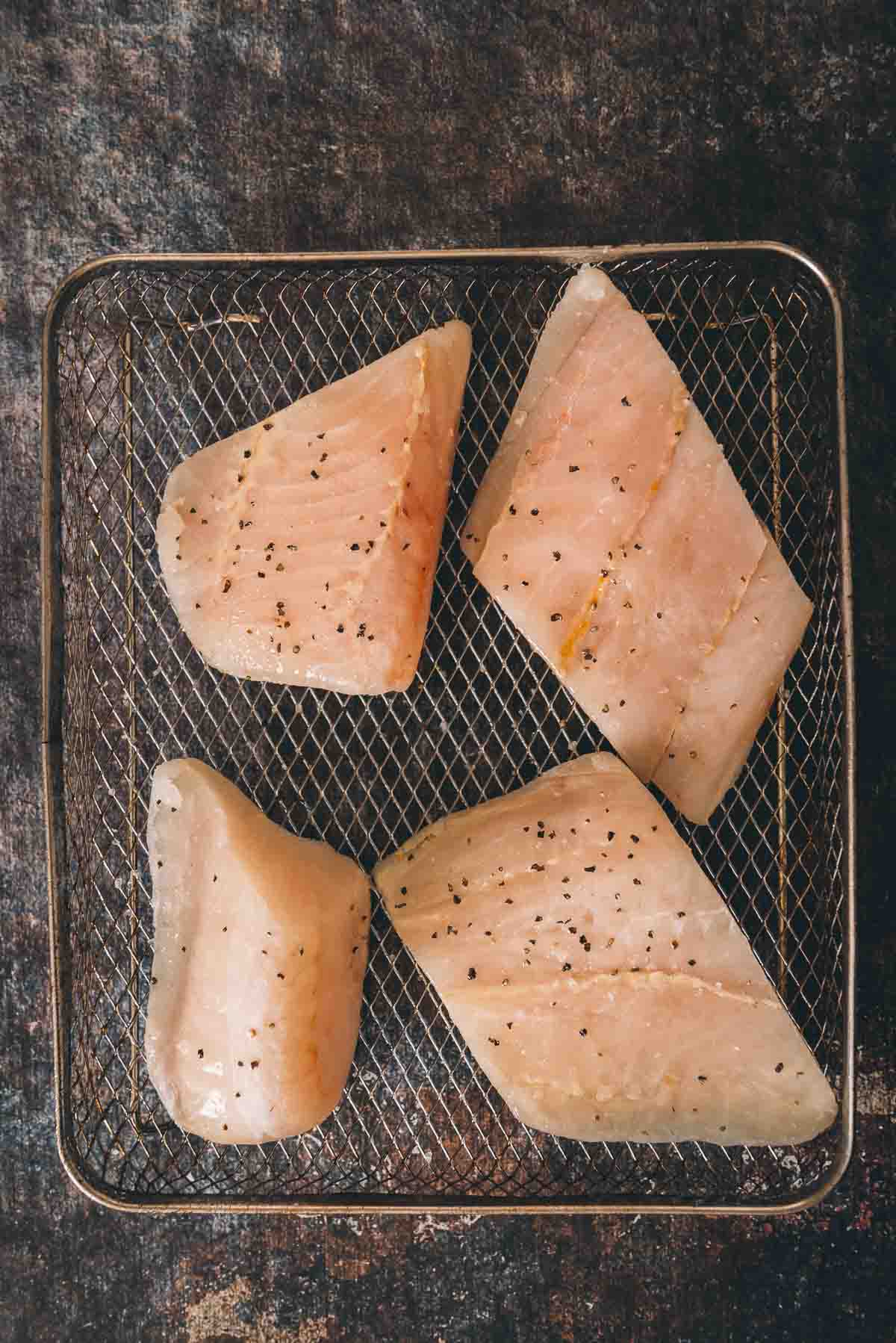 Cod filets in a air fryer basket.