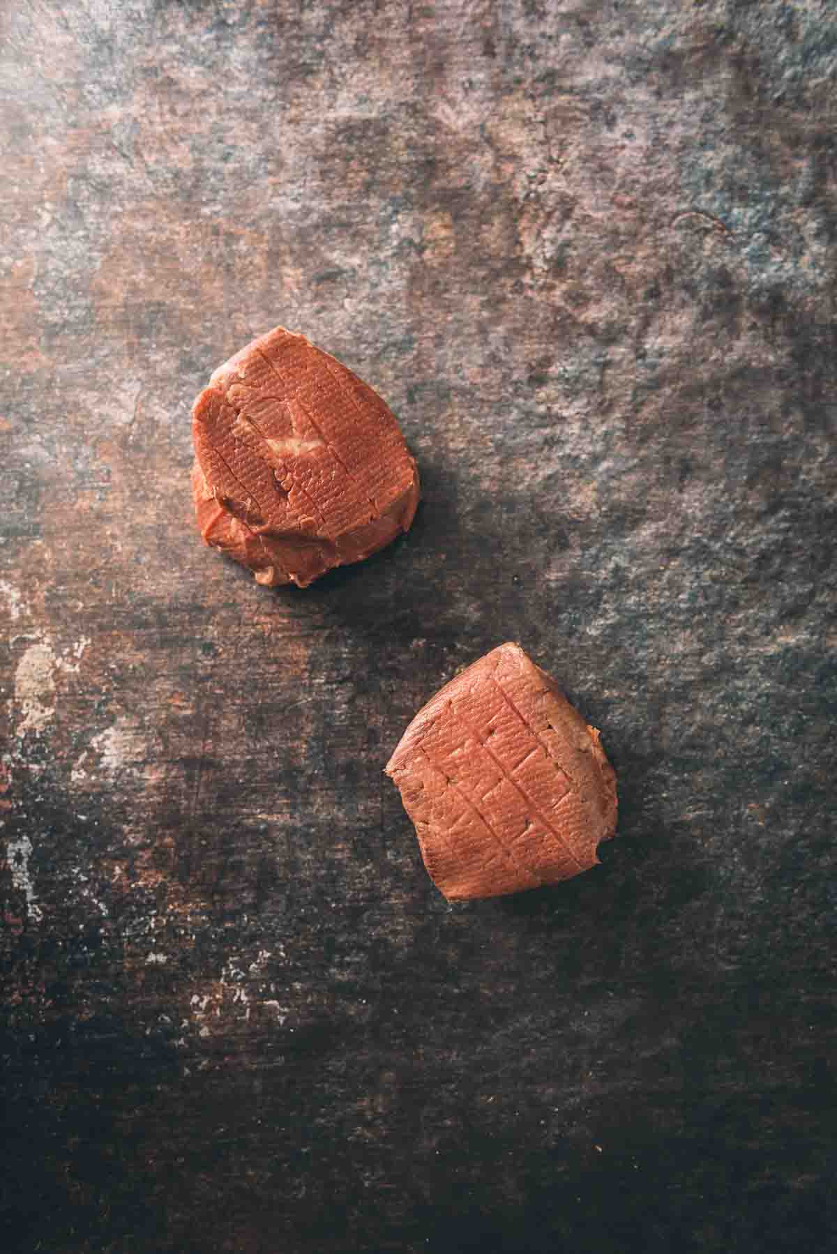 Sous vide filet mignons removed from water bath to show how color isn't desirable until steaks are seared. 