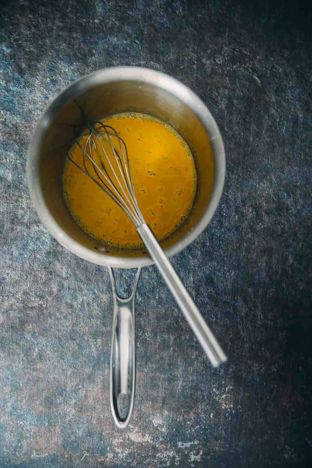 Egg yolks whisked in a sauce pan.