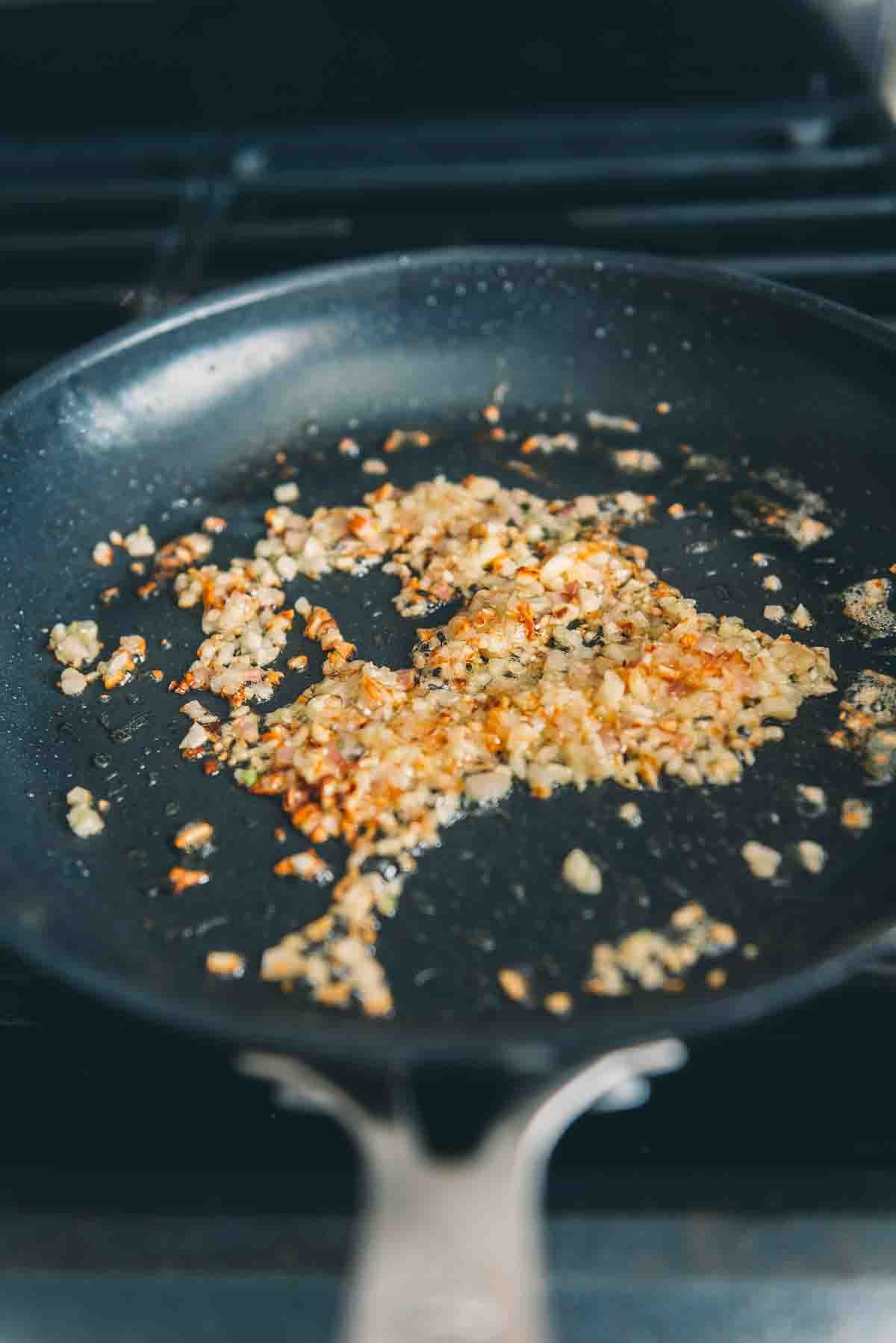 Shallots sauteeing in skillet. 