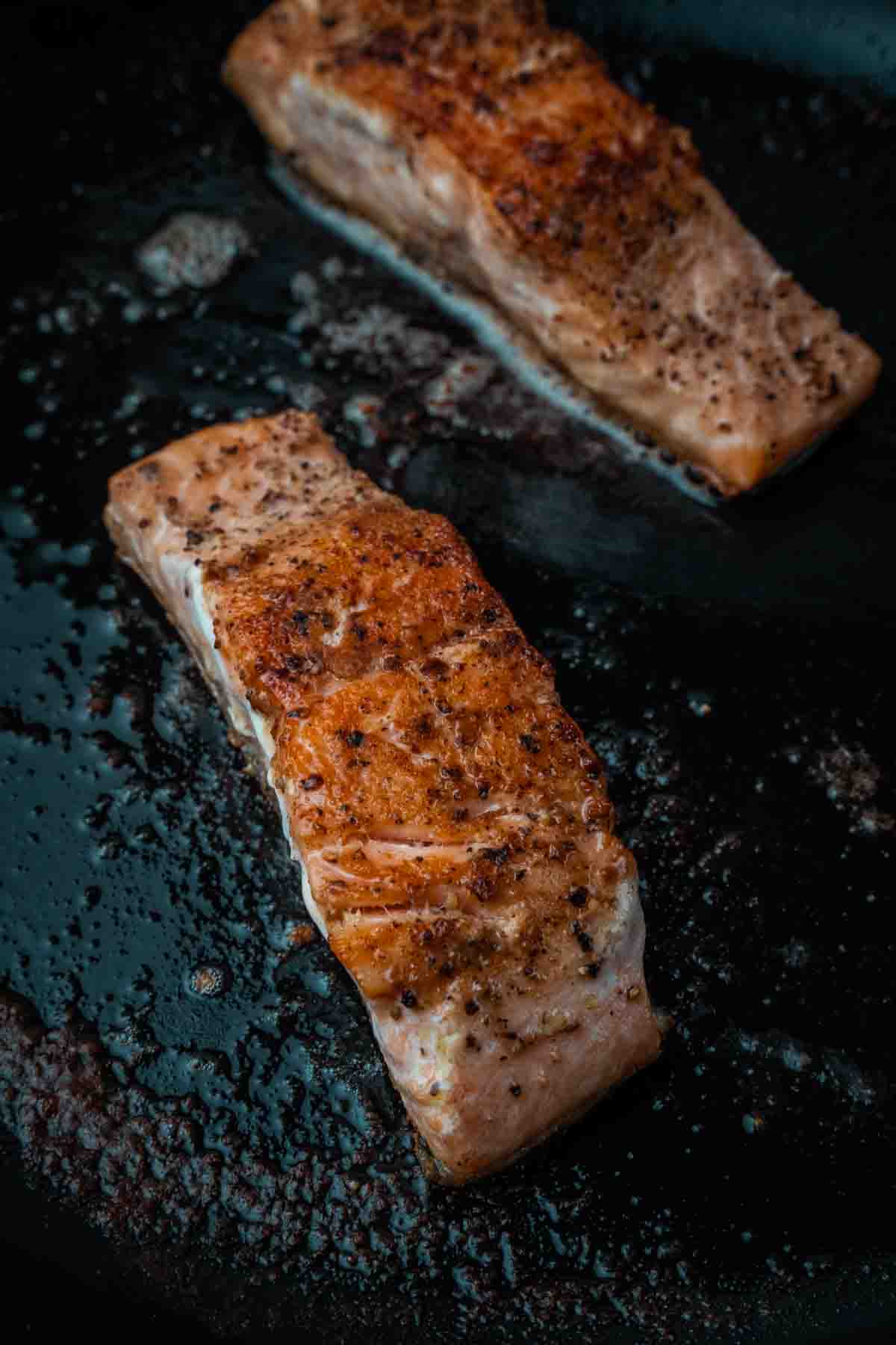 Close up of seared salmon in a pan.