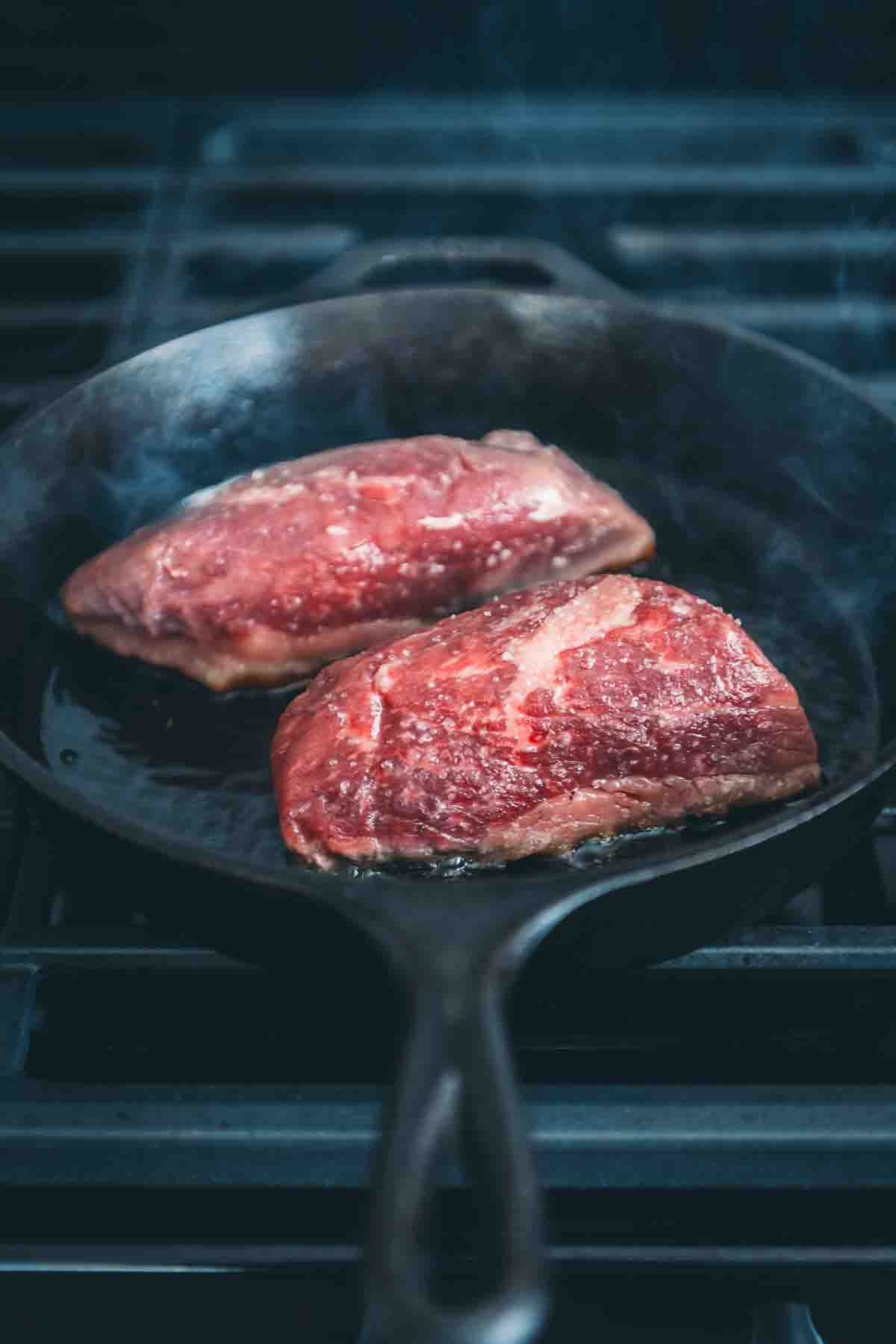Individual steaks in a cast iron pan.