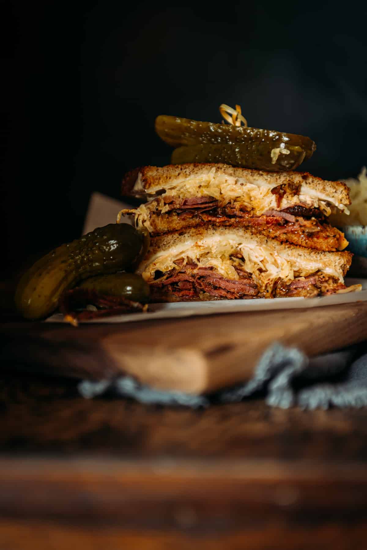 Corned beef sandwich stacked high with a pickle on top.