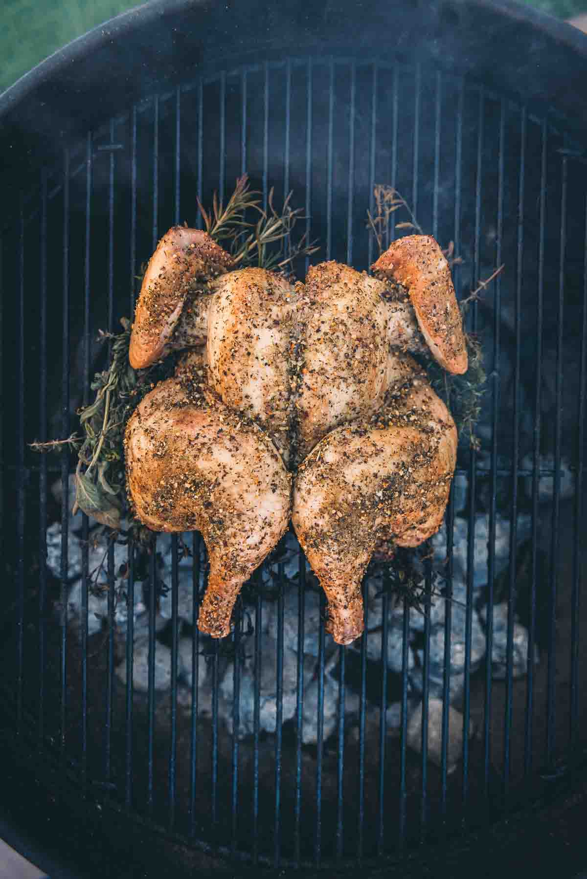 Overhead shot of spatchcock chicken over a bed of charcoal.