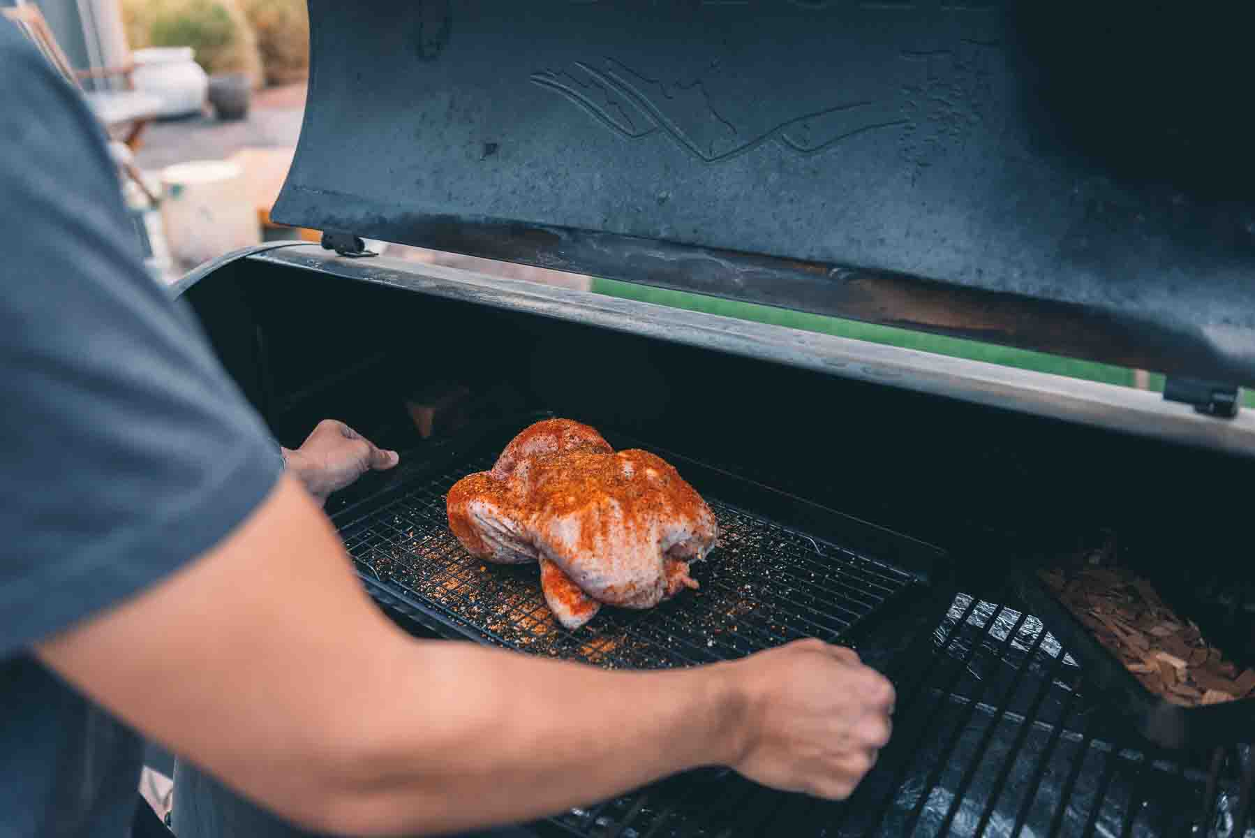 Placing a chicken on the grill grates. 