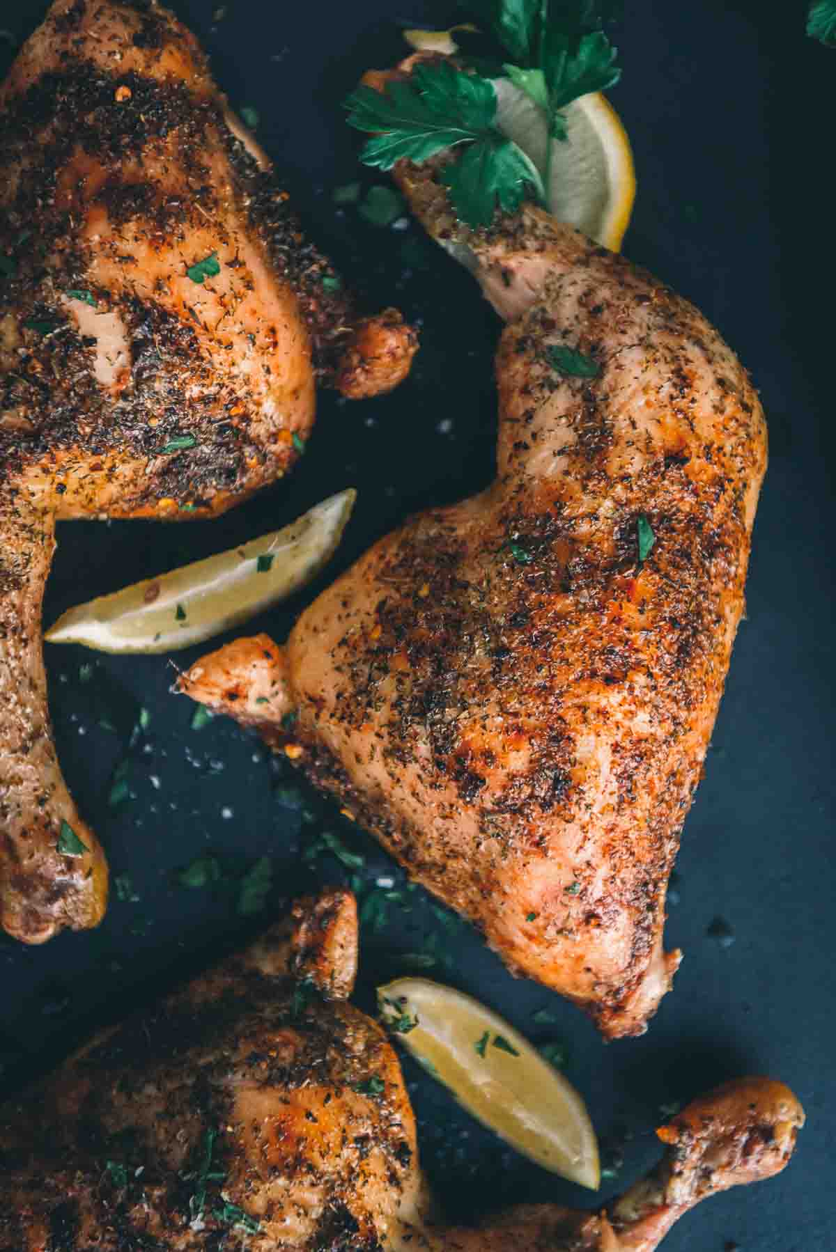 Close up of a baked chicken leg showing crisp skin and a light herb crust.