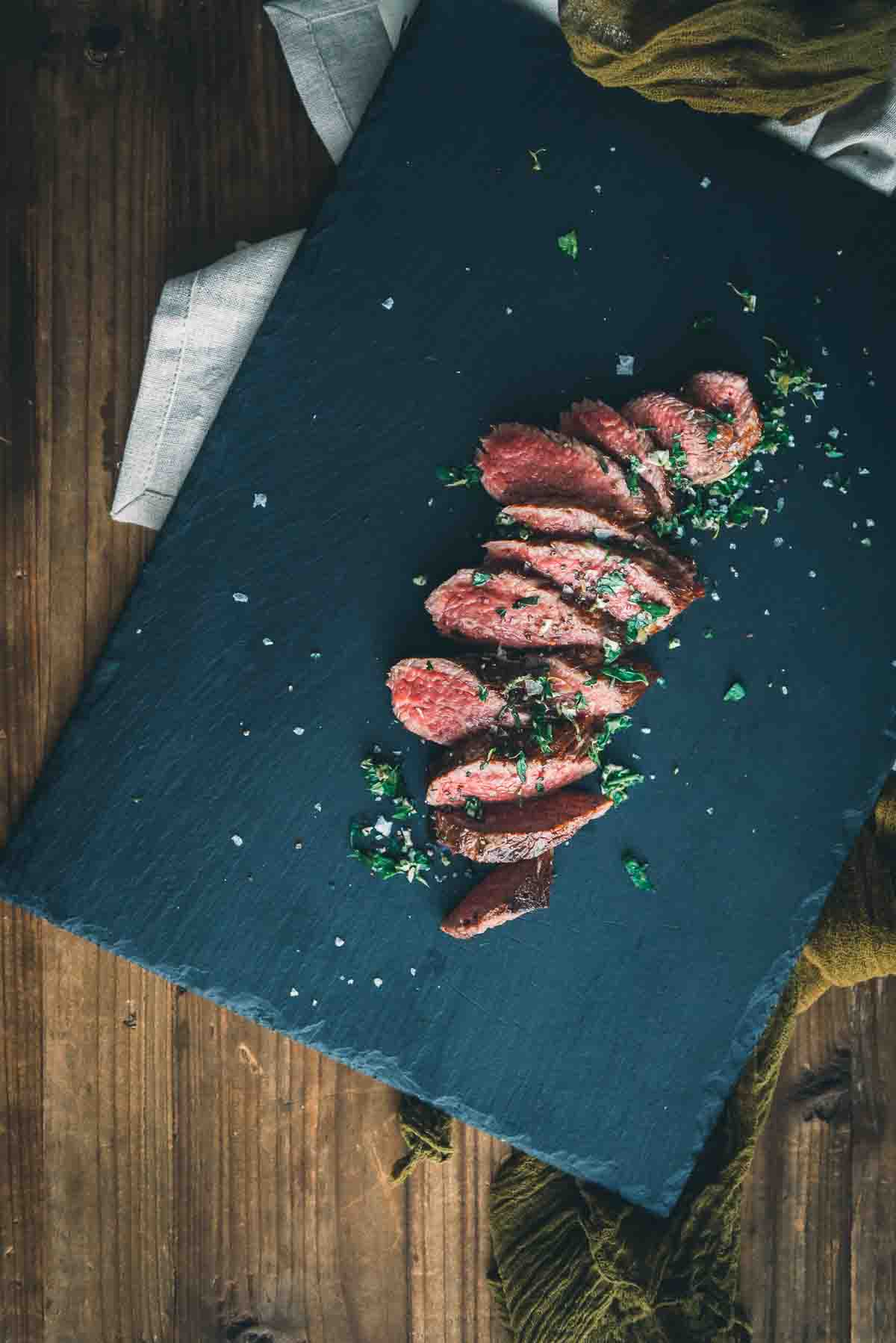 Overhead shot of sliced teres major on a black slate board and wooden table. 