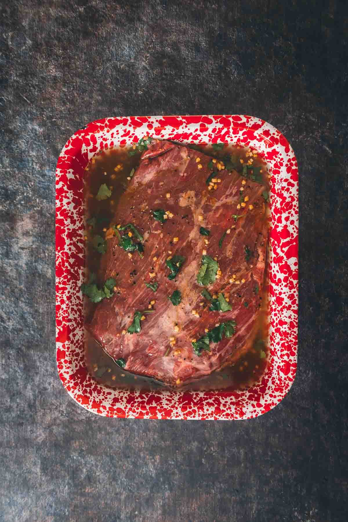 Flank steak in a pan of marinade. 