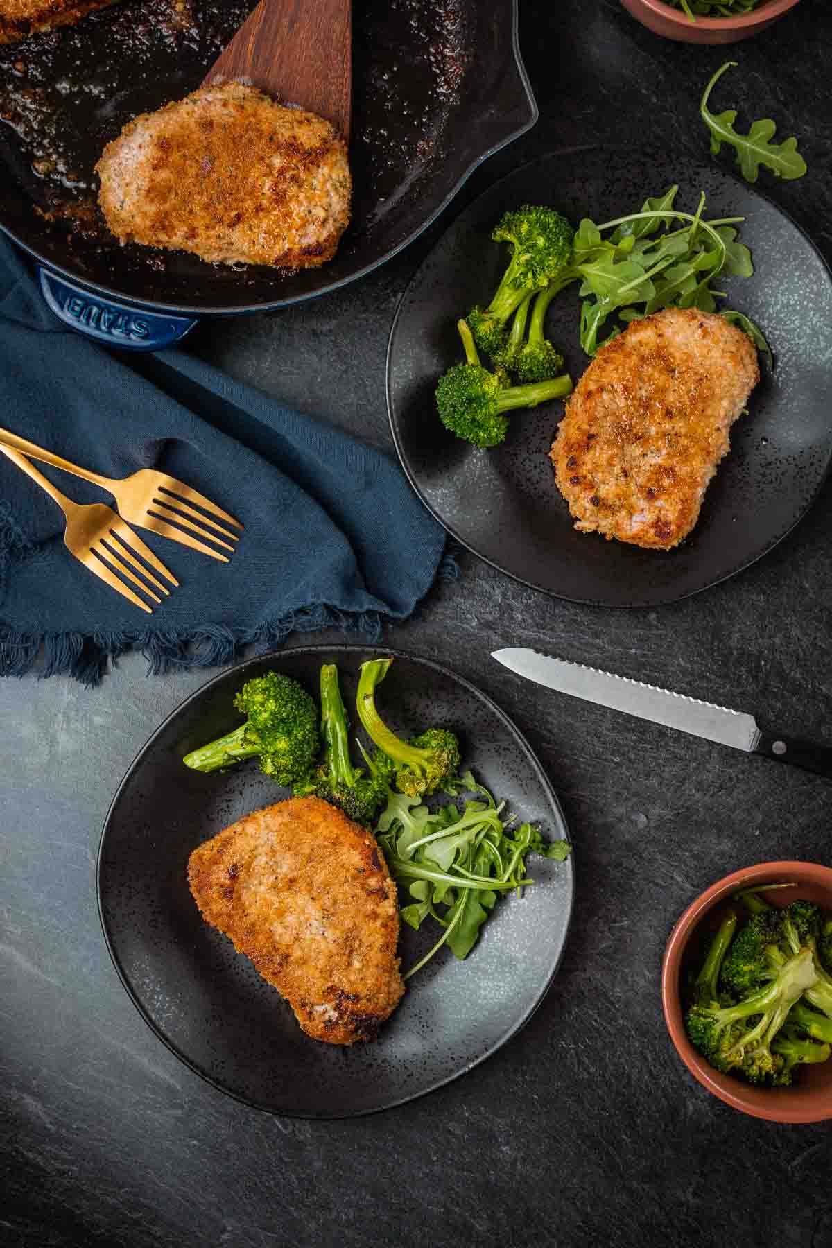 Overheat of table with plates of crispy baked pork and veggies. 