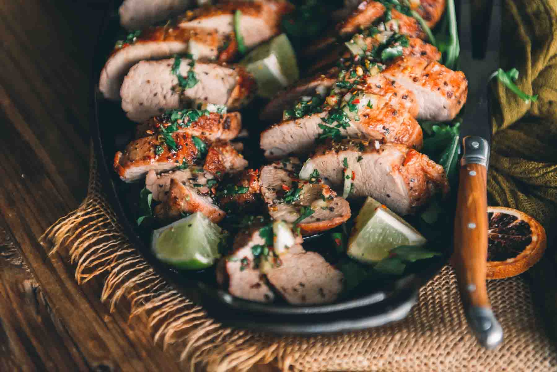 Side shot of sliced pork tenderloin to show seared crust and tender light pink center. 