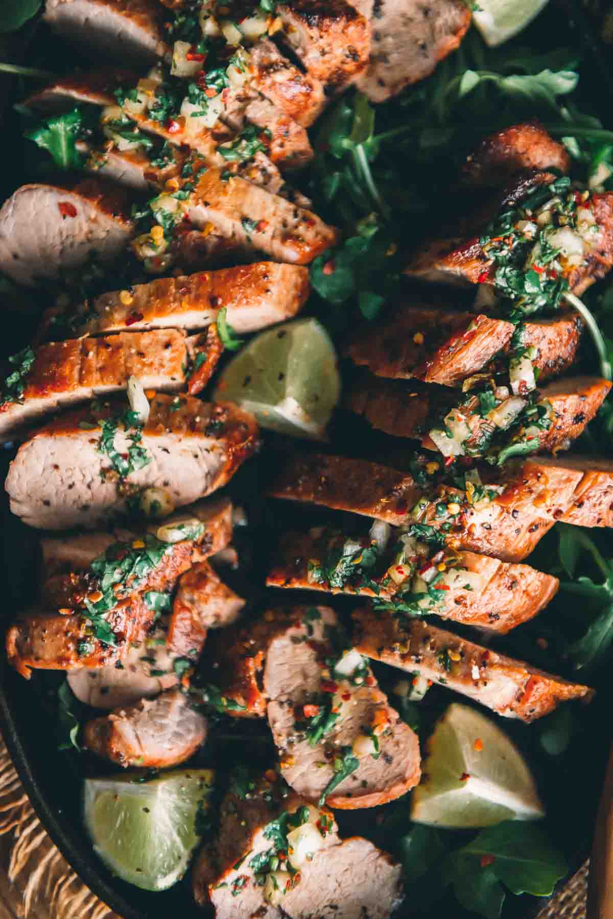 Close up overhead of sliced pork with chimichurri on top. 