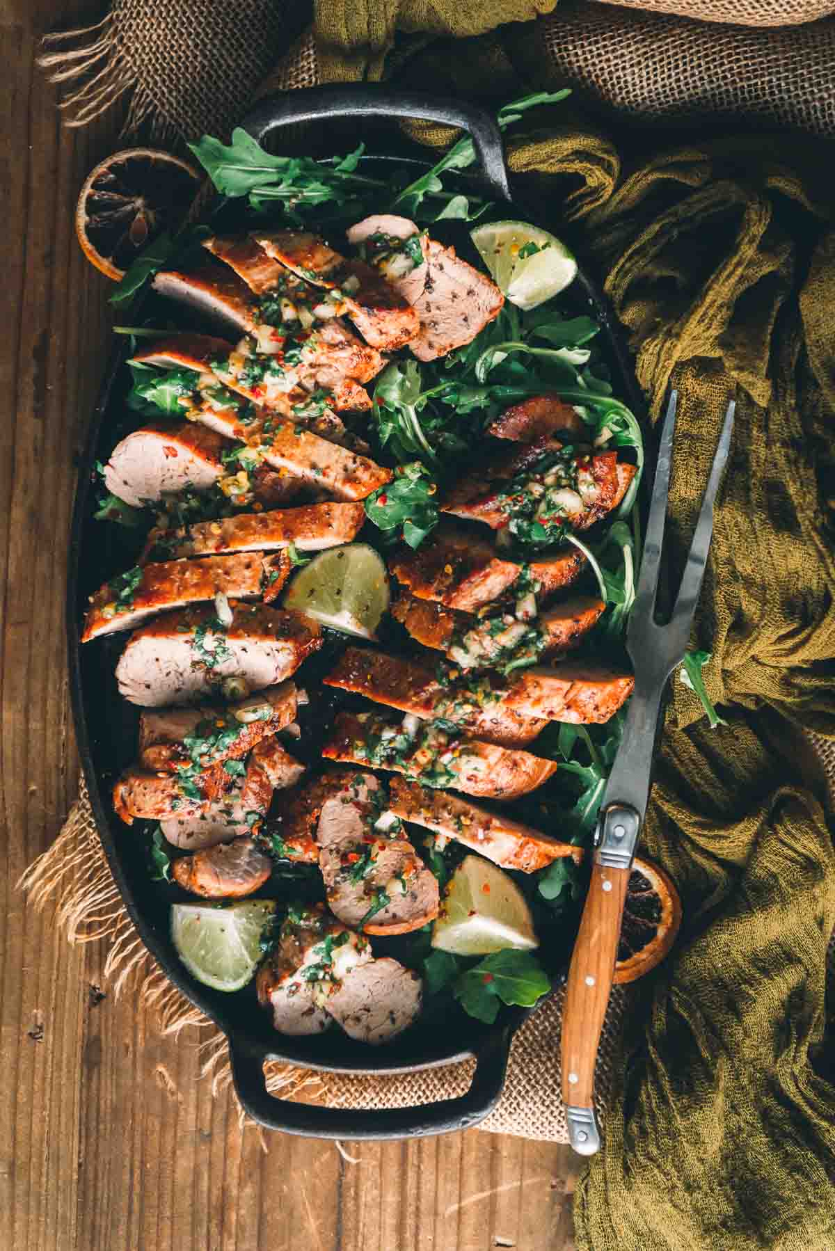 Cast iron platter of cooked pork, sliced for serving with a fork. 