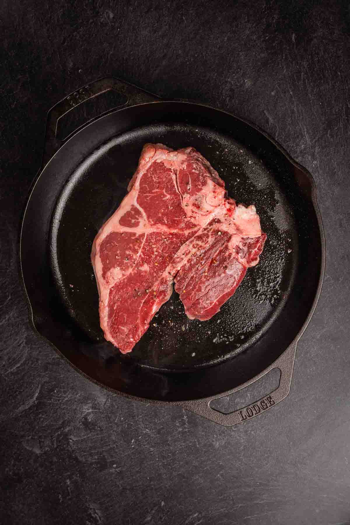 Raw porterhouse steak in a large skillet. 