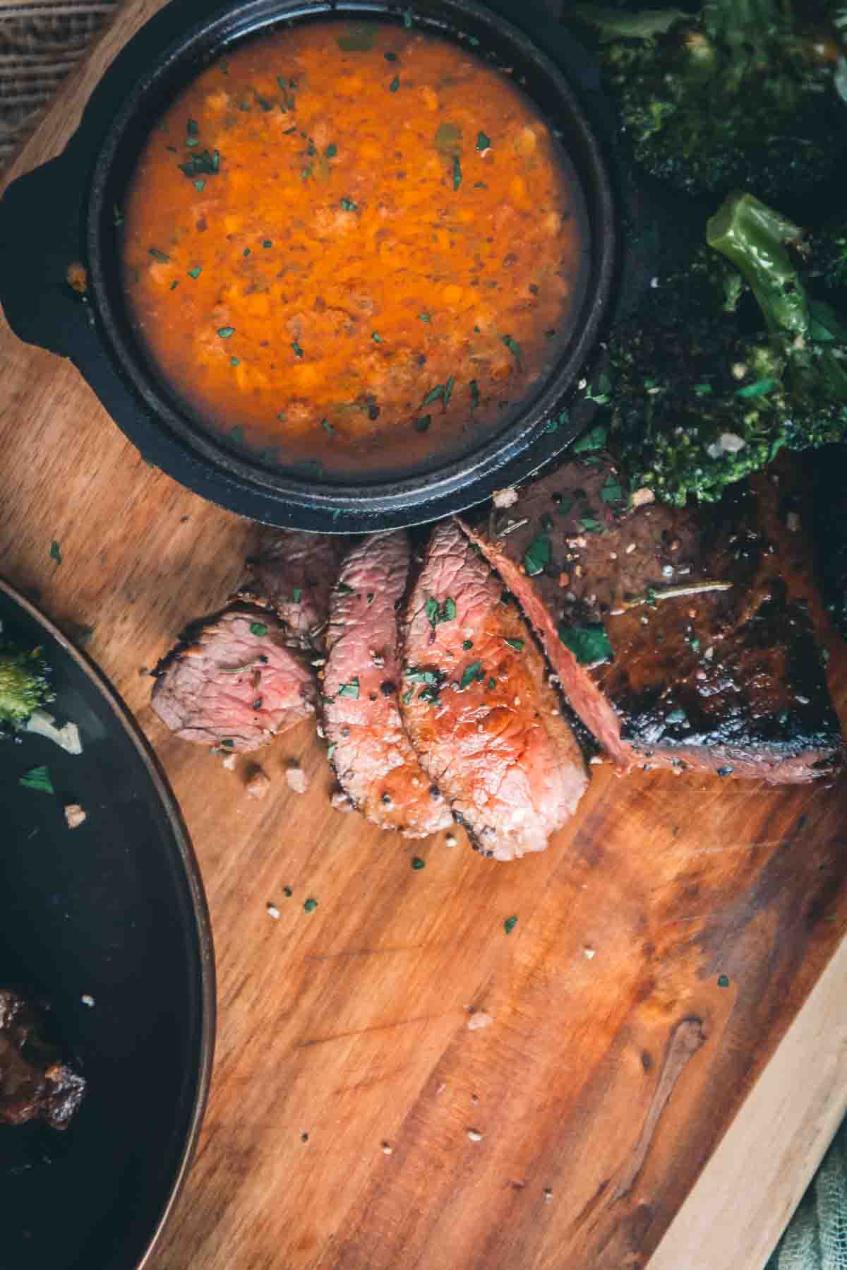 Overhead of sliced steak next to saucer of cowboy butter.