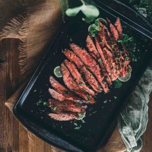 Overhead shot of sliced flank steak arranged on a platter for serving.