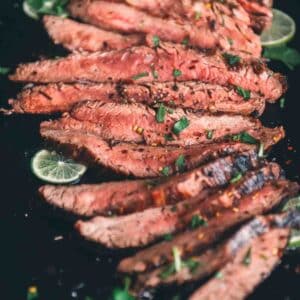 Close up of slices of grilled flank steak, showing a pink medium rare center.