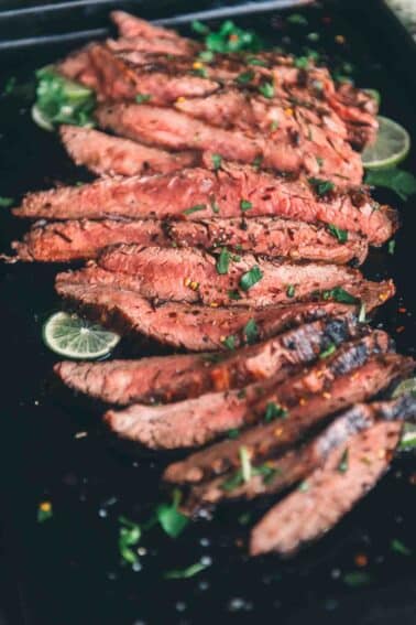 Close up of slices of grilled flank steak, showing a pink medium rare center.