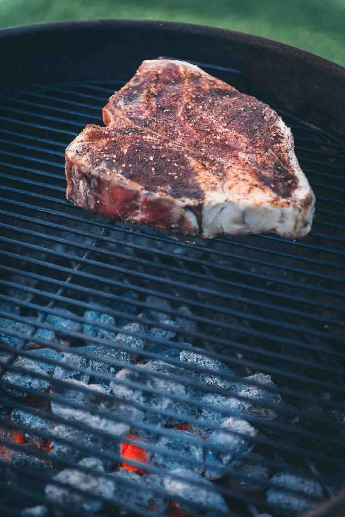 Steak on cool side of a charcoal grill. 