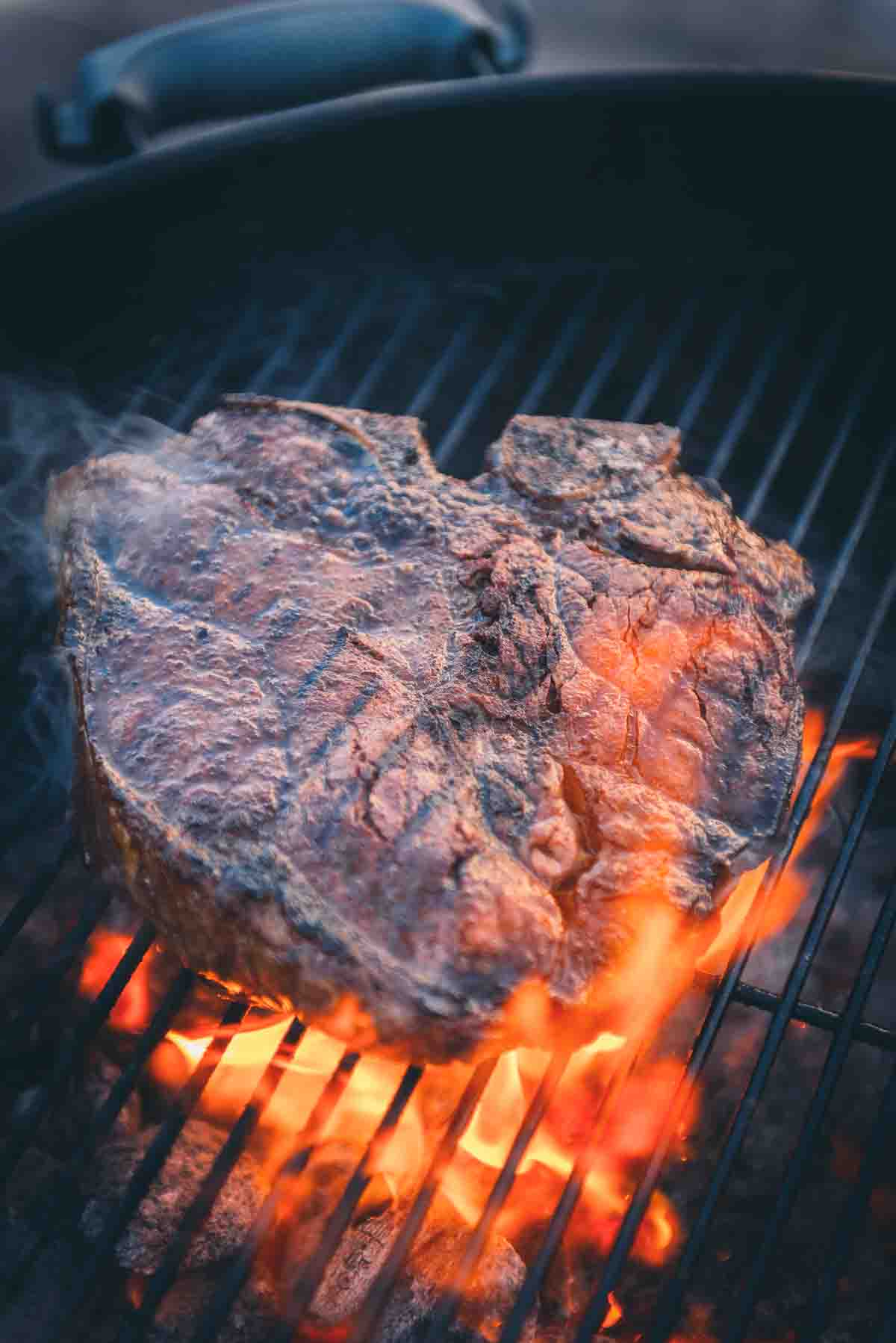 Steak being kissed by flame on the grill grates. 