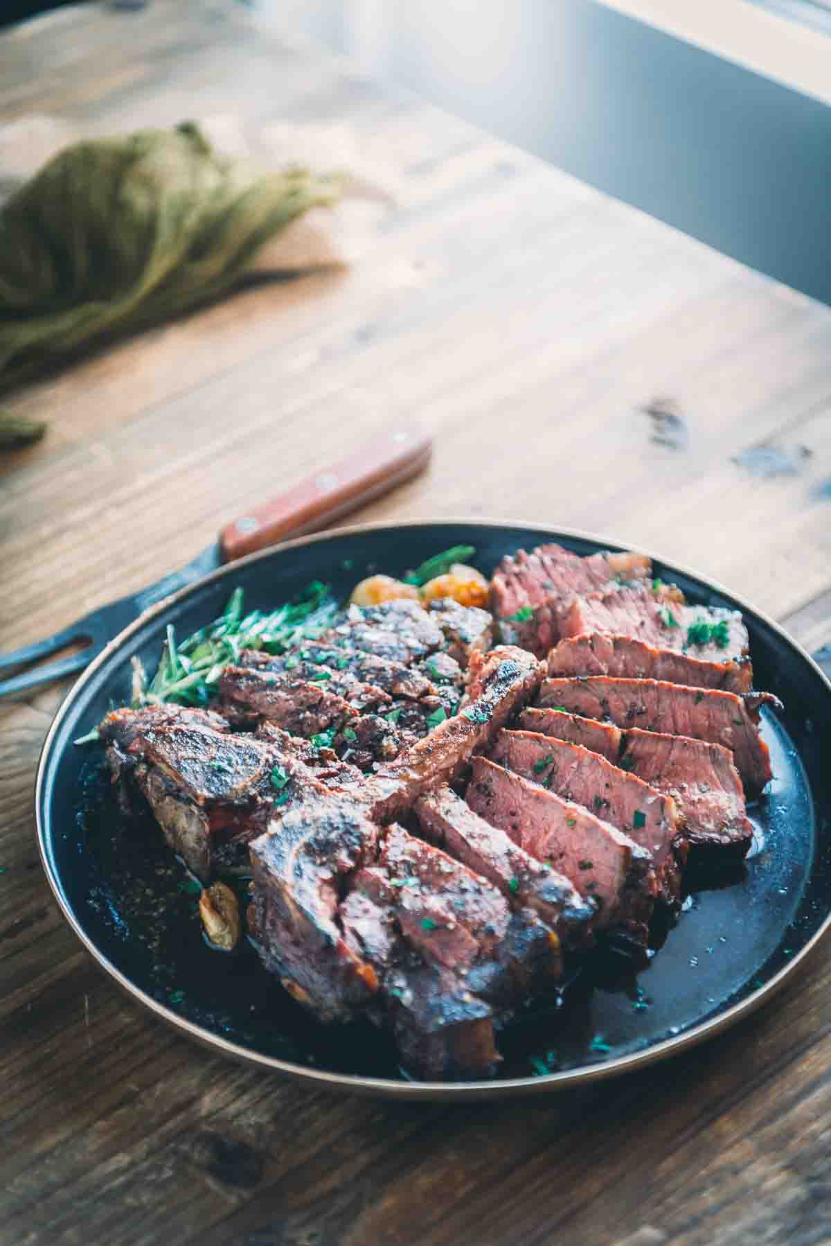 Backlit sliced porterhouse steak showing a medium-rare pink center. 