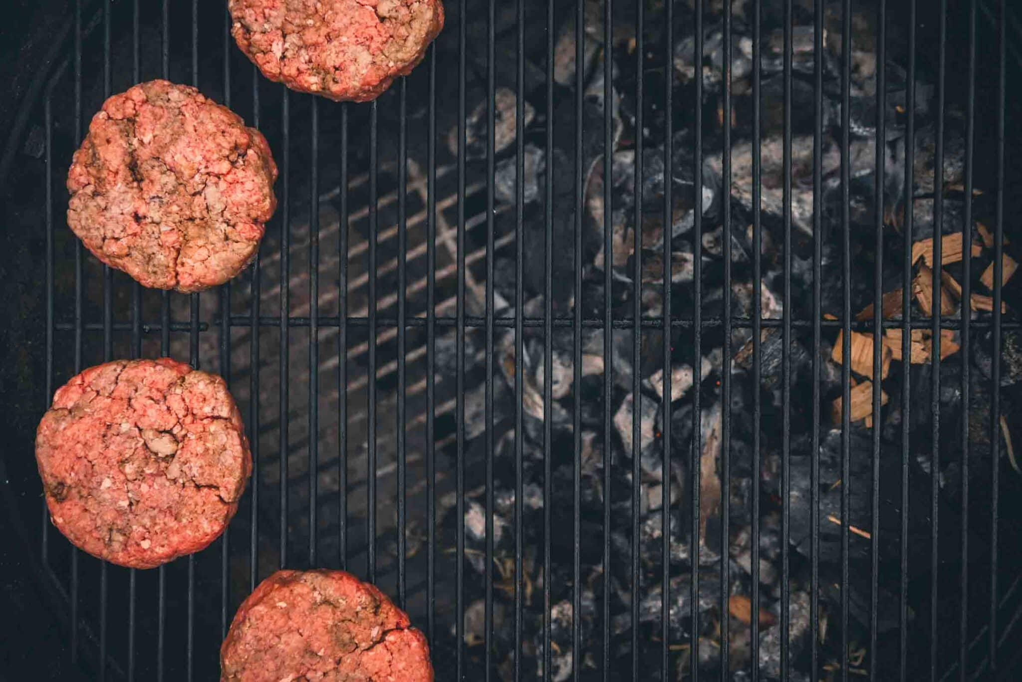 Showing burgers over indirect heat, with the coals on one side of the grill and the patties on the other. 