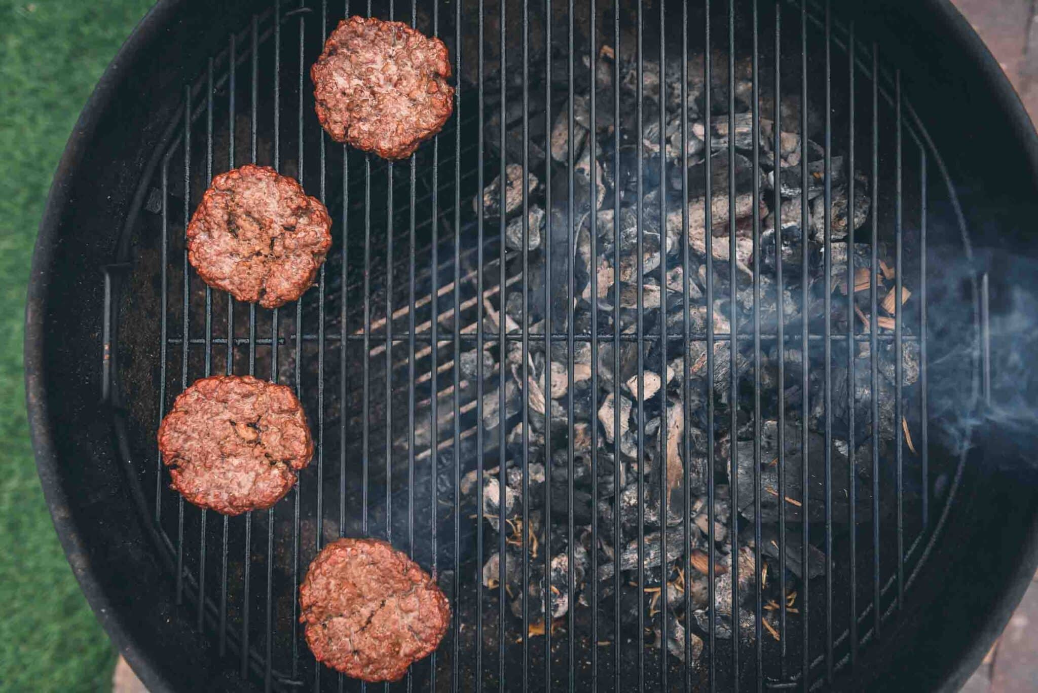 Burgers smoking over a charcoal grill. 