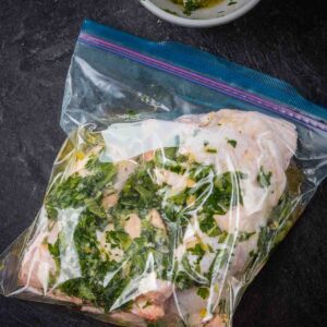 Chicken quarters in a resealable bag with marinade.