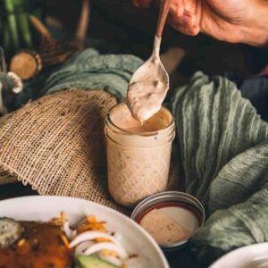 hand holding spoon dipping into dressing.