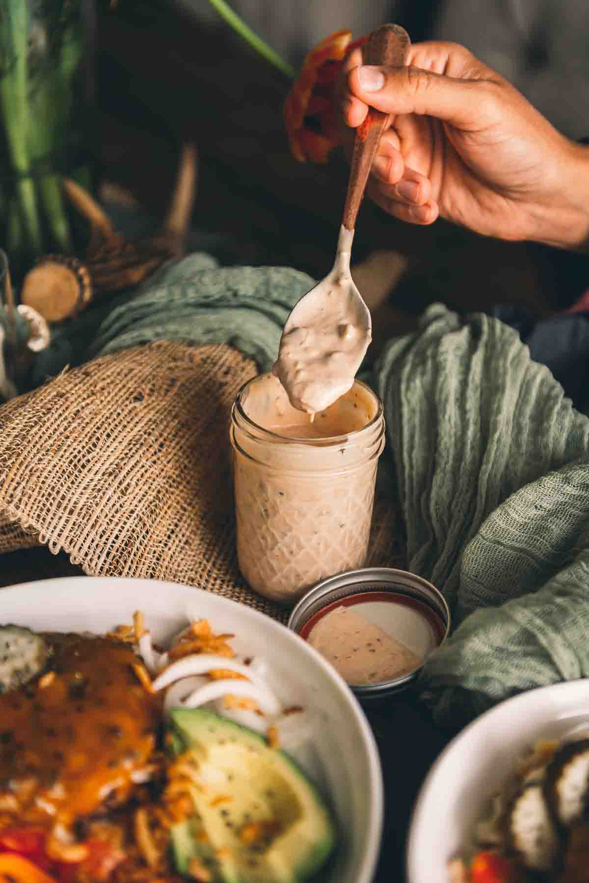 Hand holding spoon dipping into dressing.