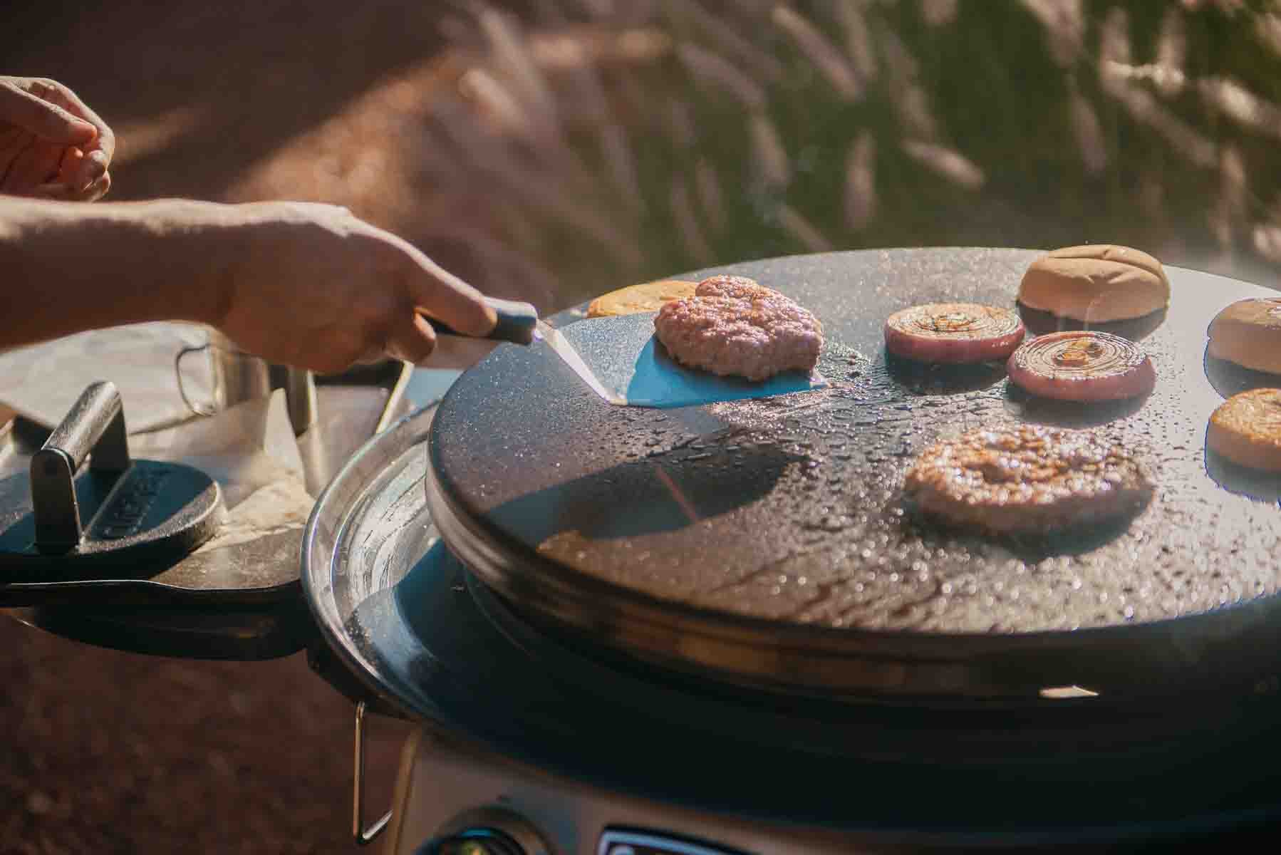 Spatula flipping a burger on a griddle. 