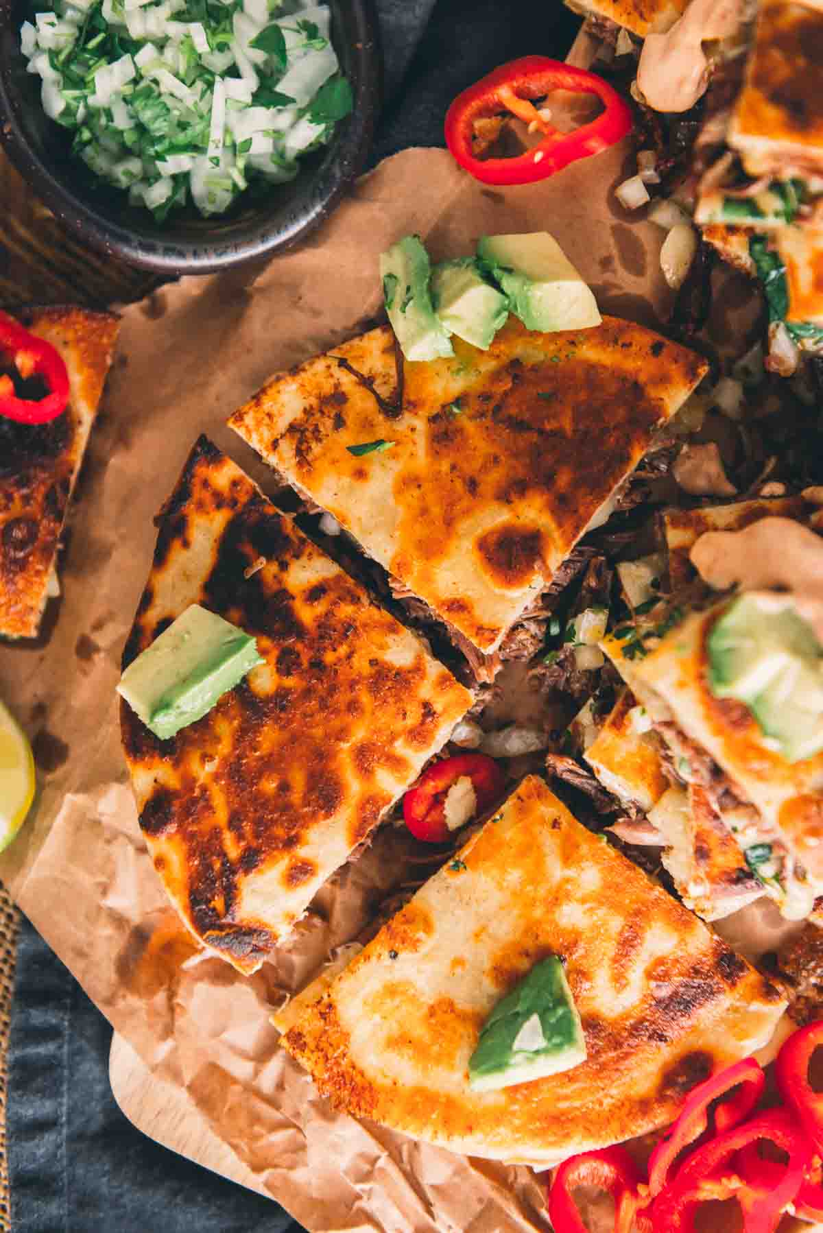 Overhead shot showing a toasty golden brown birria quesadilla sliced into wedges for serving. 