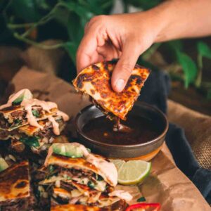 Hand dipping quesadilla wedge into the broth.