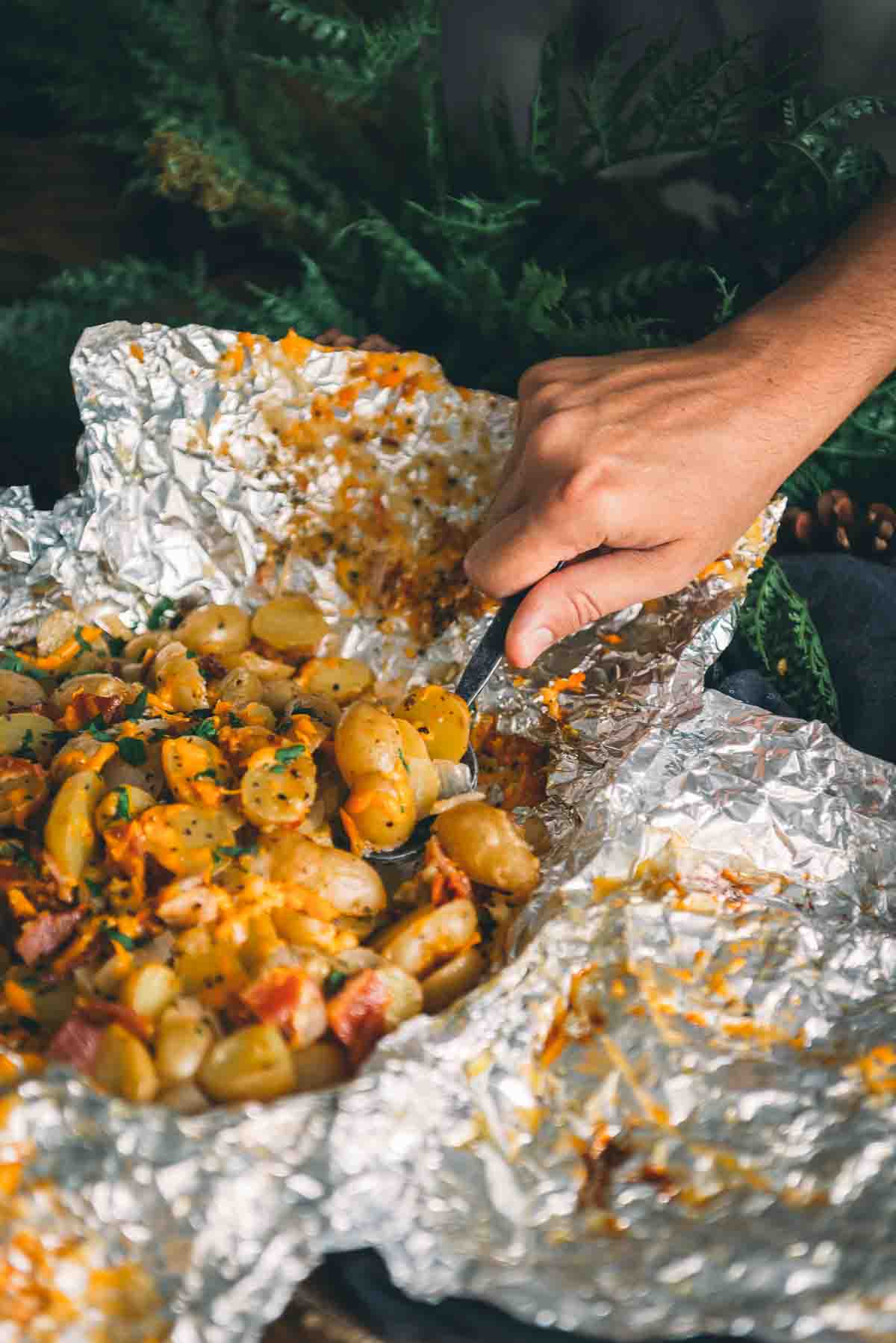 Hand spooning out a helping of potatoes.