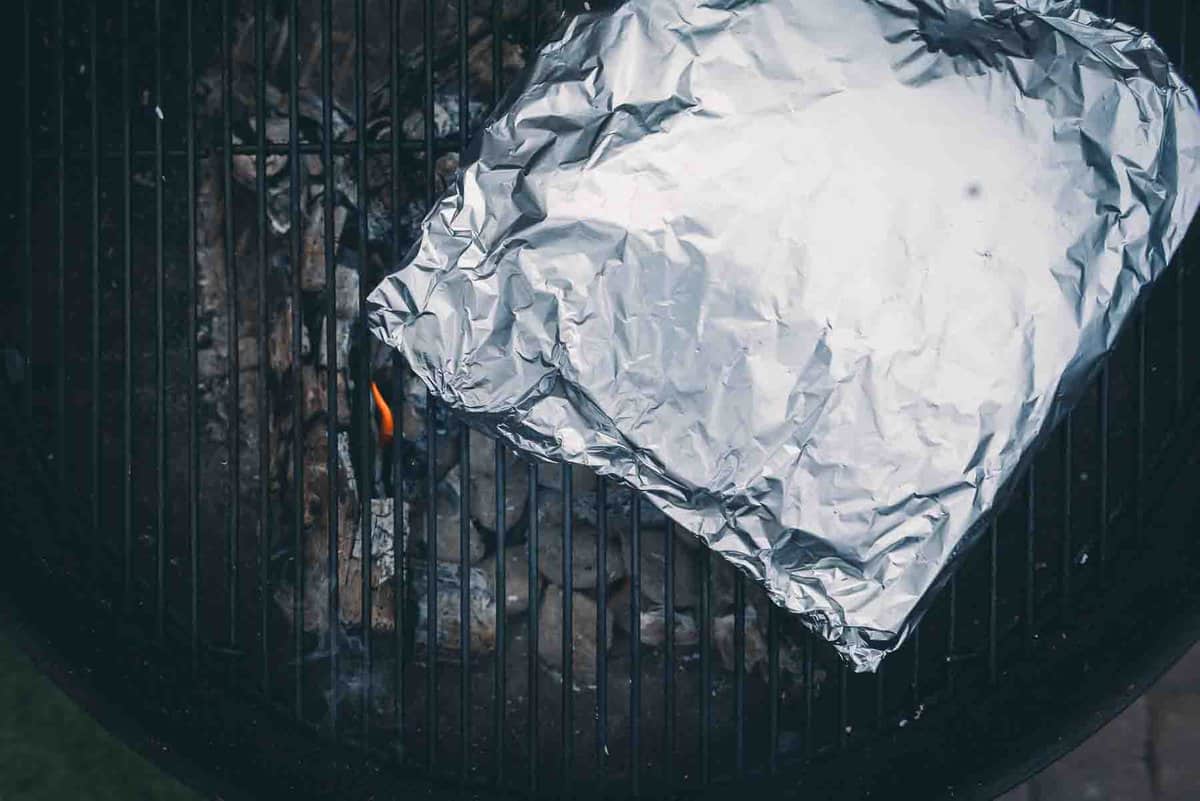 Foil pack on the grill grates over lit coals. 