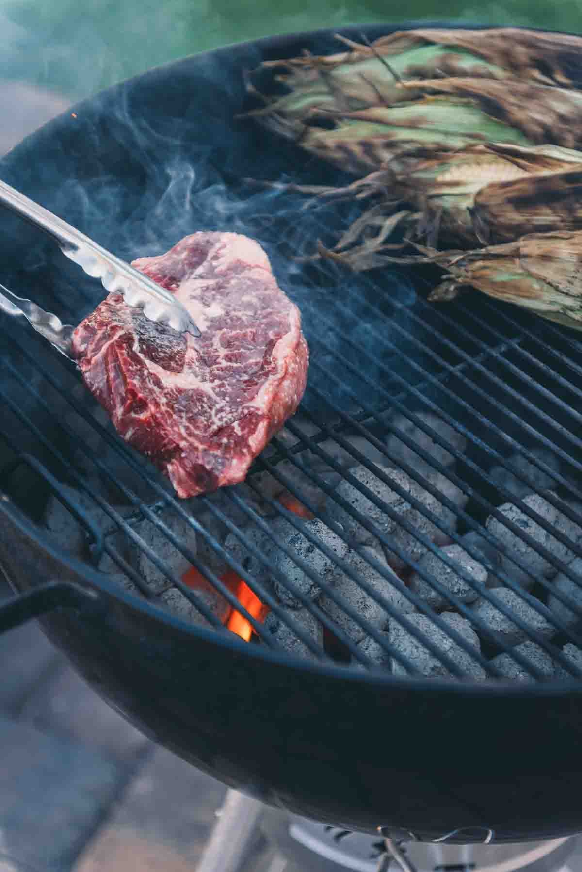 Ribeye steak going on the grill.