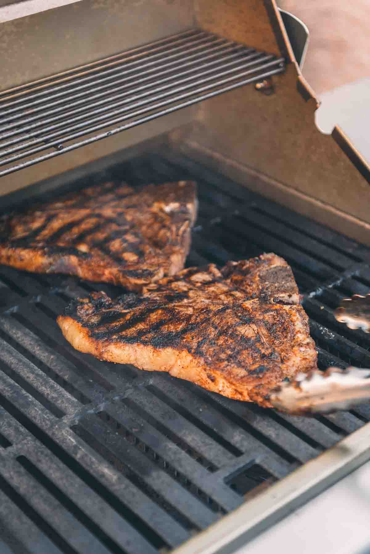 Tbone steaks on a grill grates. 