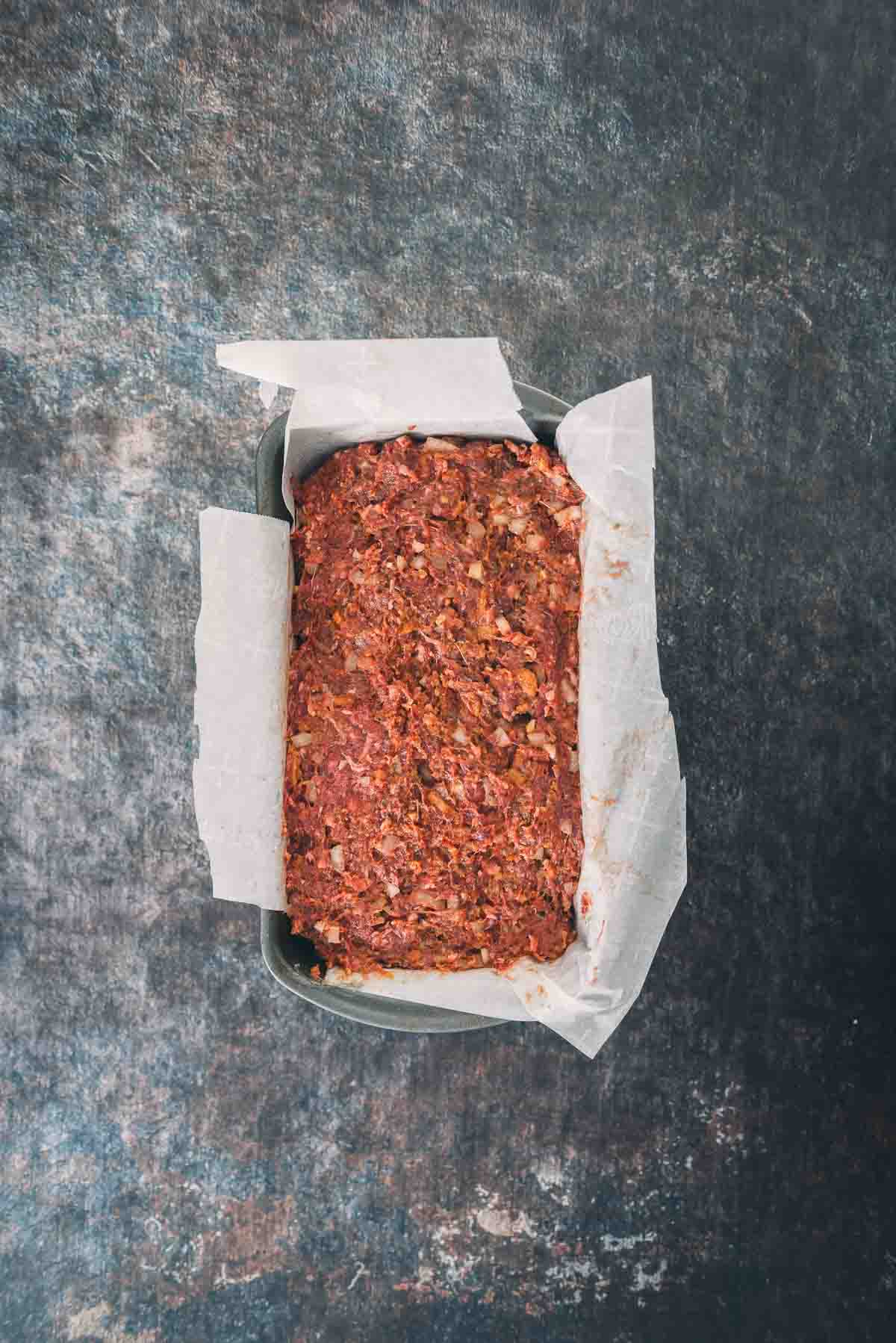 Ground deer meat and ingredients formed in a pan.