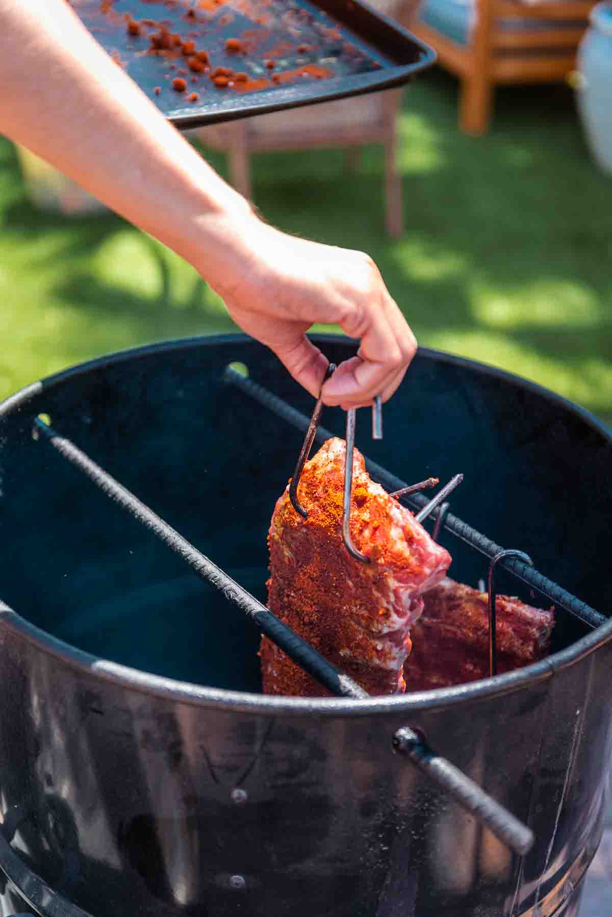 Rack of ribs being hung in a drum style smoker. 