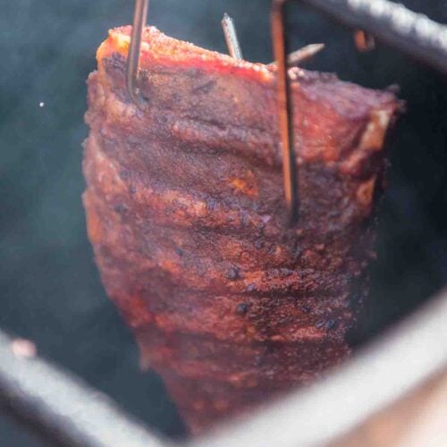 Rack of ribs hanging in the drum smoker.