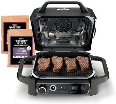 A black & decker bbq grill with steaks and a bag of spices.