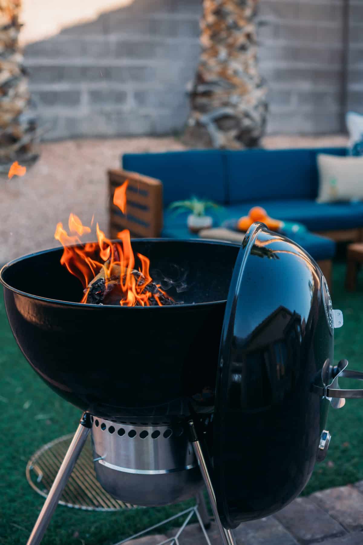 A black weber bbq grill with flames as charcoal ignites.