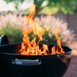 A black BBQ grill with smoking wood.