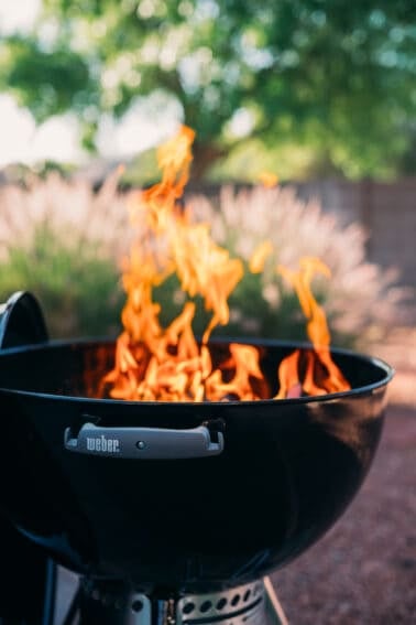 A black BBQ grill with smoking wood.