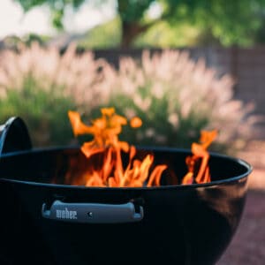 A black bbq grill with smoking wood.