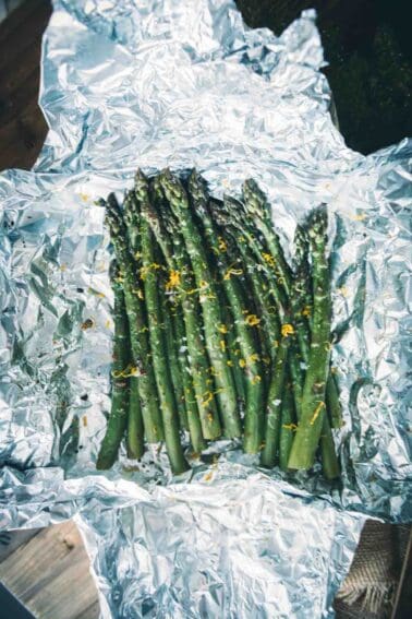 Overhead of bright green asparagus unwrapped in foil and garnished with lemon zest.