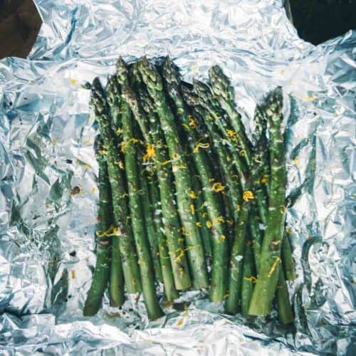 Overhead of bright green asparagus unwrapped in foil and garnished with lemon zest.