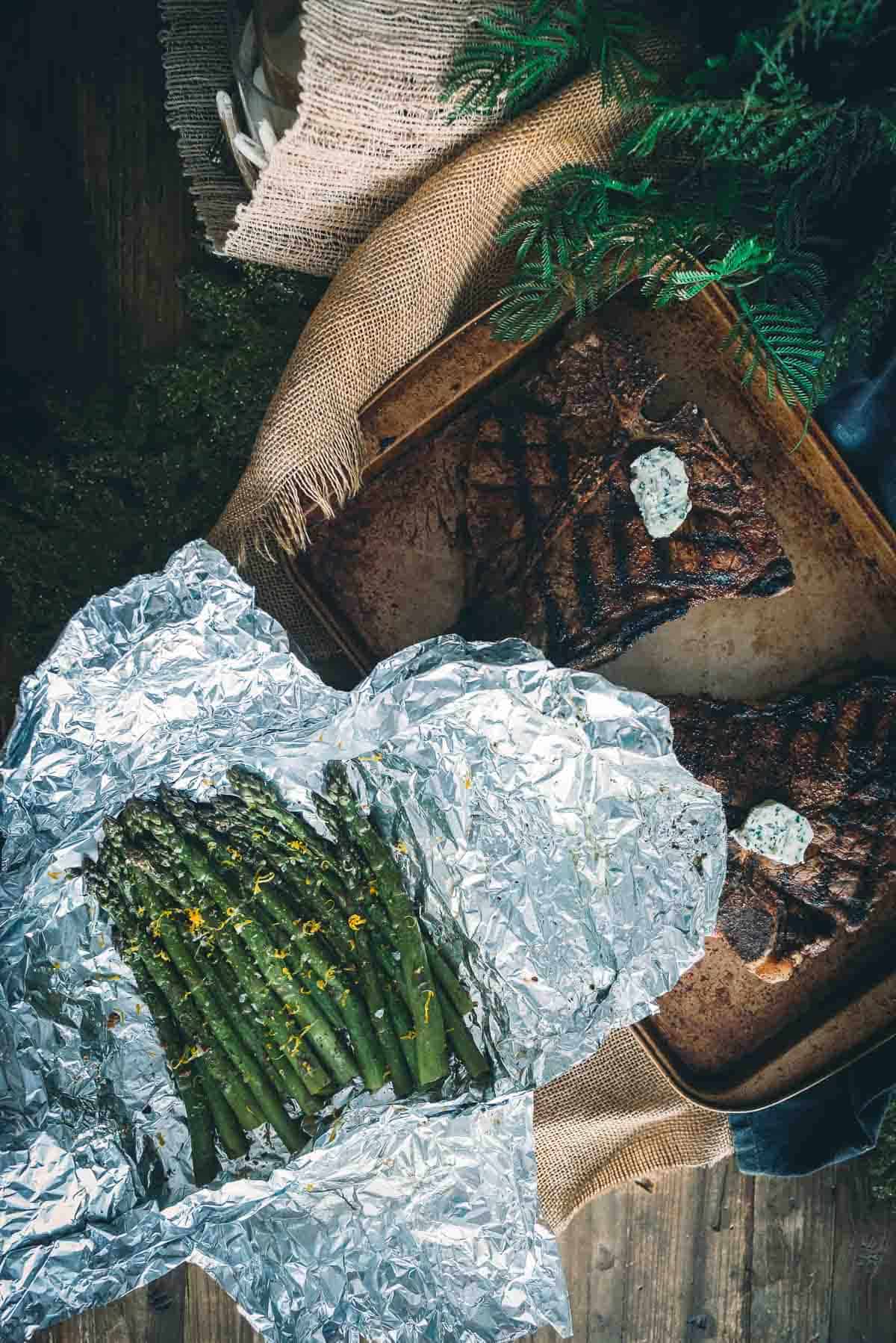 Overhead shot of table with grilled steaks and veggies for serving. 