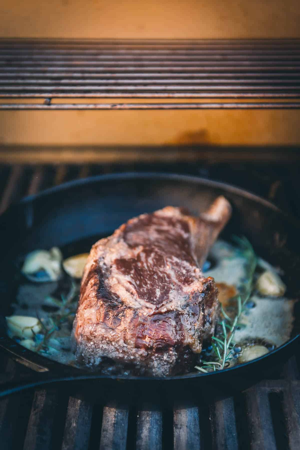 Cowboy steak searing in a cast iron skillet. 